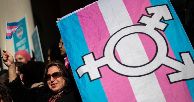 An LGBT+ activist holding the trans flag