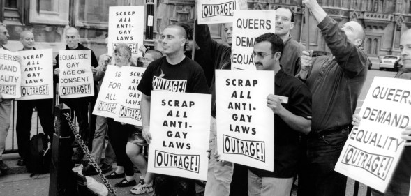 protesters holding placards with messages reading 'equalise gay age of consent' and scrap all anti-gay laws'