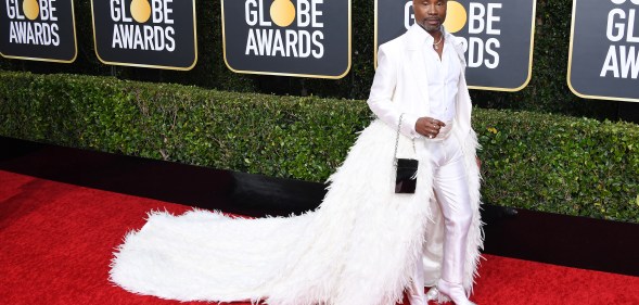 Billy Porter in a white tixuedo with feathered train on the Golden Globes 2019 red carpet