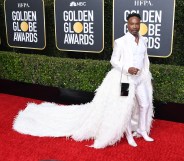 Billy Porter in a white tixuedo with feathered train on the Golden Globes 2019 red carpet
