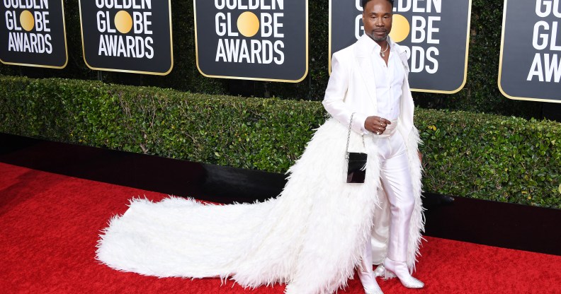 Billy Porter in a white tixuedo with feathered train on the Golden Globes 2019 red carpet