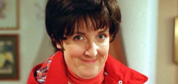 Hayley Cropper, wearing a red coat with short dark hair