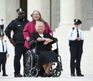 Transgender activist Aimee Stephens,with her wife behind, sits in her wheelchair outside the US Supreme Court in Washington, DC, October 8, 2019