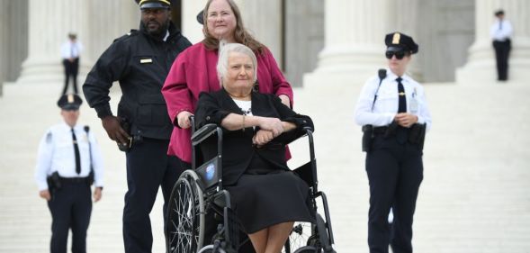 Transgender activist Aimee Stephens,with her wife behind, sits in her wheelchair outside the US Supreme Court in Washington, DC, October 8, 2019