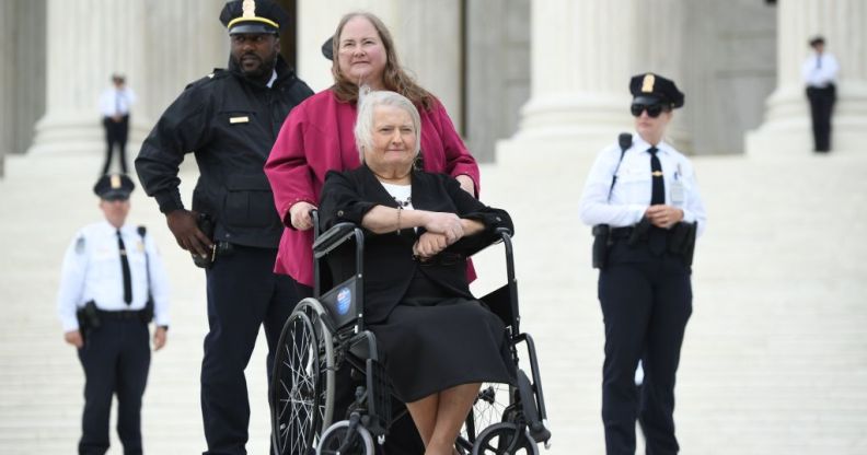 Transgender activist Aimee Stephens,with her wife behind, sits in her wheelchair outside the US Supreme Court in Washington, DC, October 8, 2019