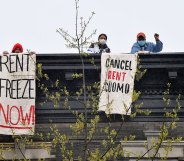 Two people on rent strike holding 'rent freeze now' and 'cancel rent Cuomo' banners