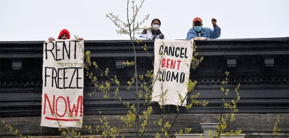 Two people on rent strike holding 'rent freeze now' and 'cancel rent Cuomo' banners