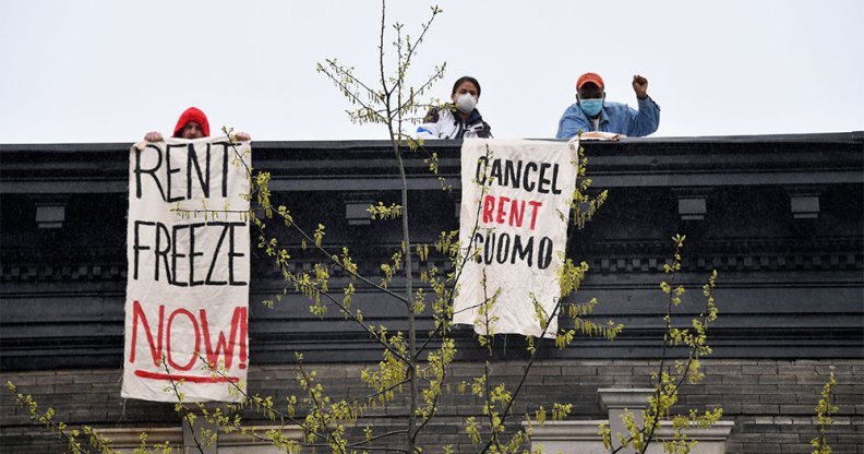 Two people on rent strike holding 'rent freeze now' and 'cancel rent Cuomo' banners