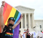 A man waves a rainbow flag in front of the Supreme Court.