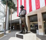 A statue of John Wayne is on display beneath an American flag in John Wayne Airport, located in Orange County, on June 28, 2020 in Santa Ana, California. Orange County