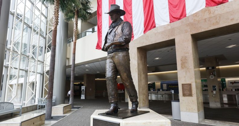 A statue of John Wayne is on display beneath an American flag in John Wayne Airport, located in Orange County, on June 28, 2020 in Santa Ana, California. Orange County