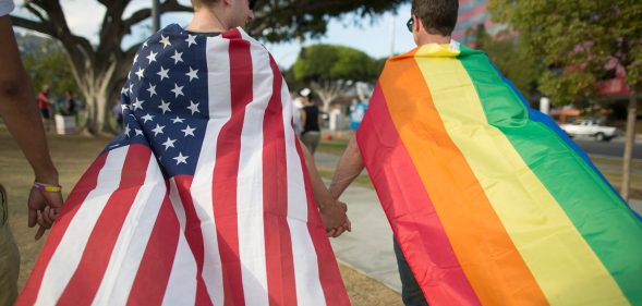A couple holds hands, draped in flags, as they celebrate the Supreme Court ruling on same-sex marriage on June 26, 2015 in West Hollywood, California.