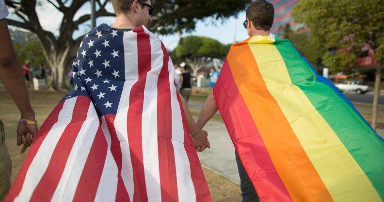 A couple holds hands, draped in flags, as they celebrate the Supreme Court ruling on same-sex marriage on June 26, 2015 in West Hollywood, California.