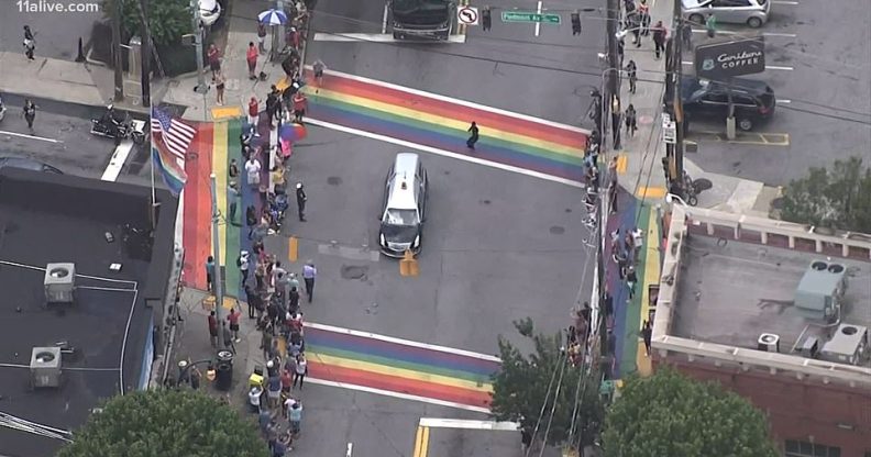 The casket of John Lewis, a towering giant in the civil rights movement, pauses as crowds cheer at a Pride flag-inspired crossroads in Atlanta, US. (Screen capture via Facebook)