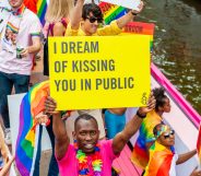 A black man holds a placard on the boat of Amnesty International during Amsterdam's famous canal pride parade