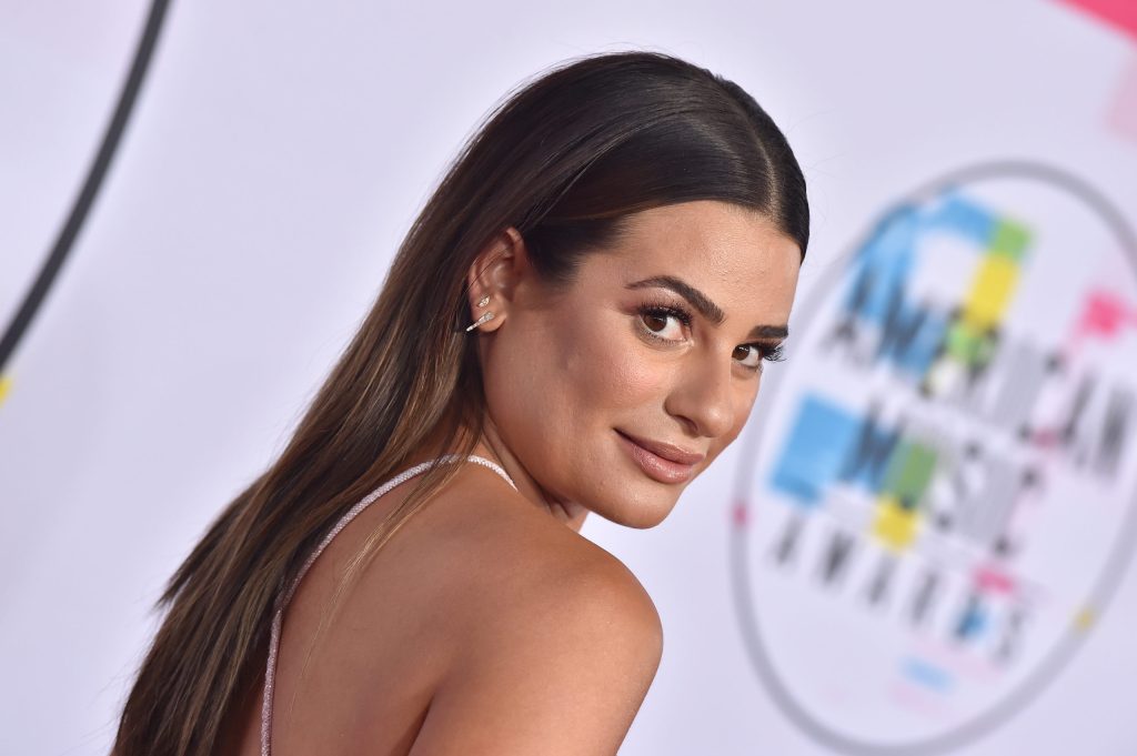 Actor Lea Michele wearing a backless top looks over her shoulder as she poses for a photograph