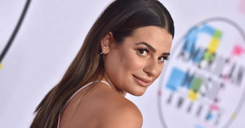 Actor Lea Michele wearing a backless top looks over her shoulder as she poses for a photograph