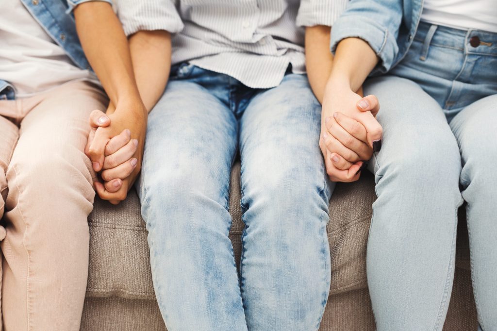 Three people hold hands in a closeup image