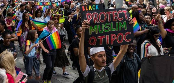 Man holding a 'protect Muslim QTIPOC' placard in a Pride parade