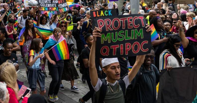 Man holding a 'protect Muslim QTIPOC' placard in a Pride parade