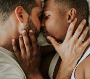 This stock photo shows two men kissing and cuddling in bed