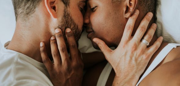 This stock photo shows two men kissing and cuddling in bed