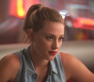 Lili Reinhart as Betty Cooper in Riverdale, wearing a sleeveless denim shirt, red lipstick and a ponytail