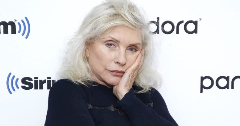 Debbie Harry in a black jumper with silver hair, resting her face on her hand
