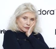Debbie Harry in a black jumper with silver hair, resting her face on her hand
