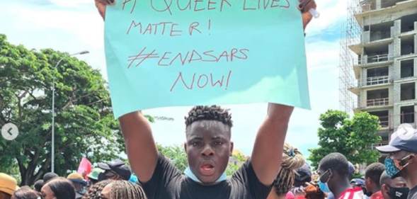 Matthew Blaise holding a placard reading 'Queer Lives Matter! End SARS now!'