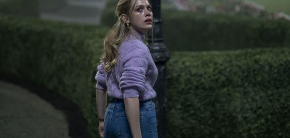 Dani standing in front of some bushes in the Haunting of Bly Manor