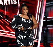 Lizzo in a black dress with the word VOTE in bold white text all over