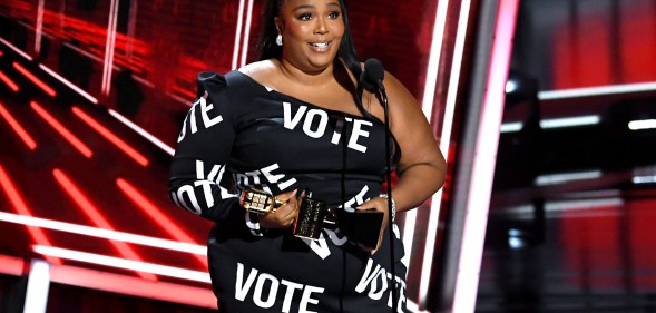 Lizzo in a black dress with the word VOTE in bold white text all over