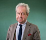 John Banville wearing a suit and tie against a green backdrop