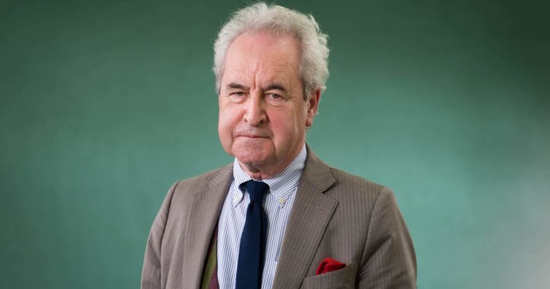 John Banville wearing a suit and tie against a green backdrop