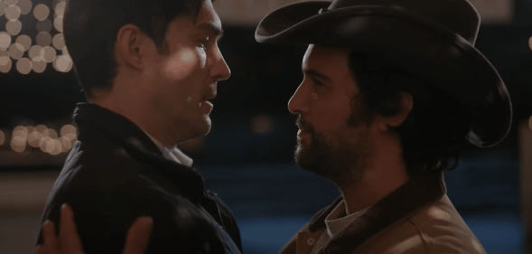 Two men embracing, one wearing a cowboy hat, in the Dashing in December trailer