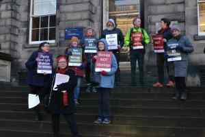 A photo showing anti-trans pressure group For Women Scotland holding placards