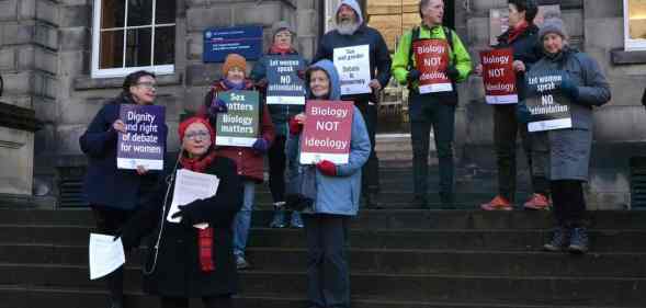 A photo showing anti-trans pressure group For Women Scotland holding placards