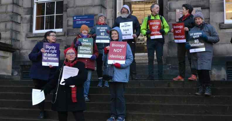 A photo showing anti-trans pressure group For Women Scotland holding placards