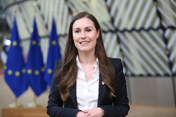 Sanna Marin is smiling in front of EU flags.