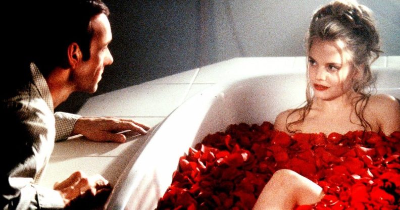 Kevin Spacey leering over a naked young woman in a bath filled with flowers