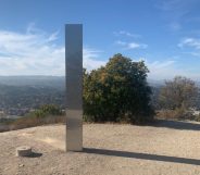 A tall, slim silver monolith at the top of an empty hill