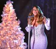 Mariah Carey performs in a white diamanté dress with a white Christmas tree behind her