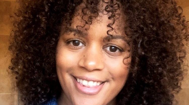 Porsche Smith, HR Business Partner at Sony Music UK wearing a denim shirt and smiling at the camera