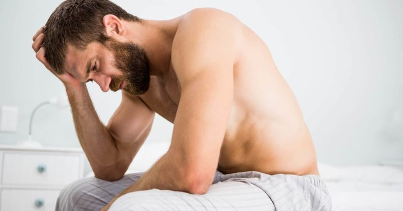 Topless man sitting with his head in his hands