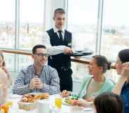 Waiter serves people food in a restaurant