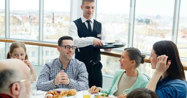 Waiter serves people food in a restaurant