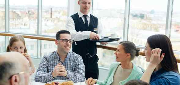 Waiter serves people food in a restaurant