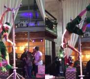 Topless man dressed in elf trousers and a hat pole dancing