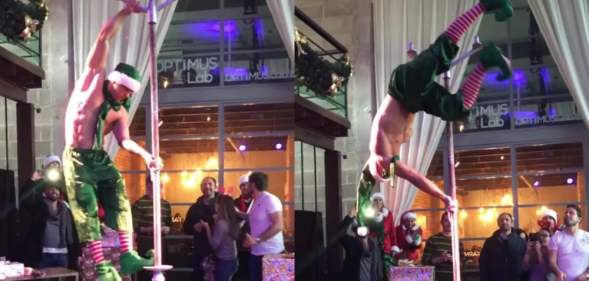 Topless man dressed in elf trousers and a hat pole dancing
